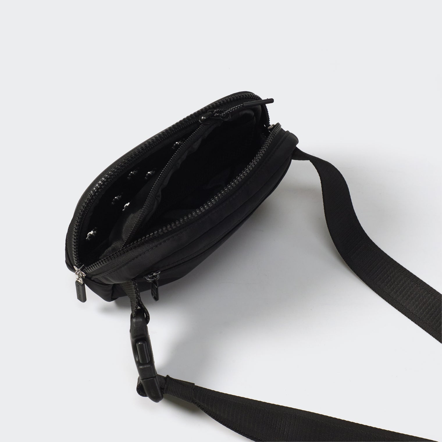 Black dual-zip belt bag open to show divided interior mesh pockets